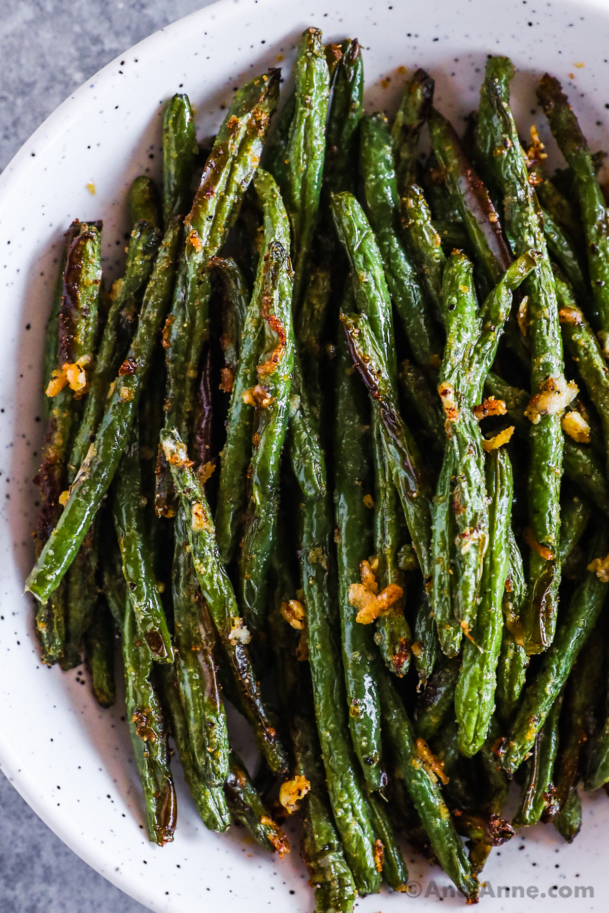 Bowl of crispy green beans with pieces of crispy parmesan cheese pieces.
