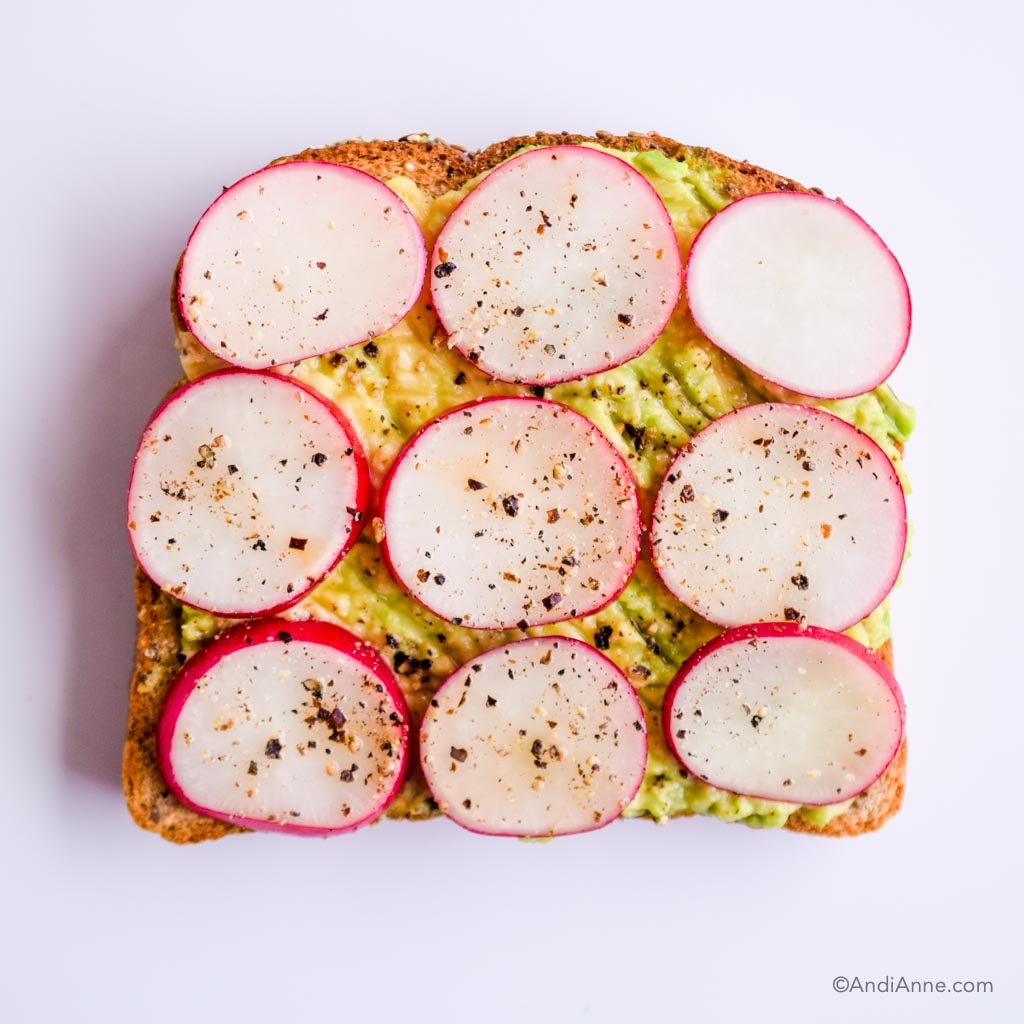 mashed avocado on toast with sliced radishes, salt and pepper on top.
