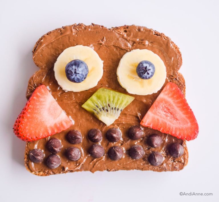 owl shaped toast with nut butter spread. Berries and chocolate chips used to create owl shape