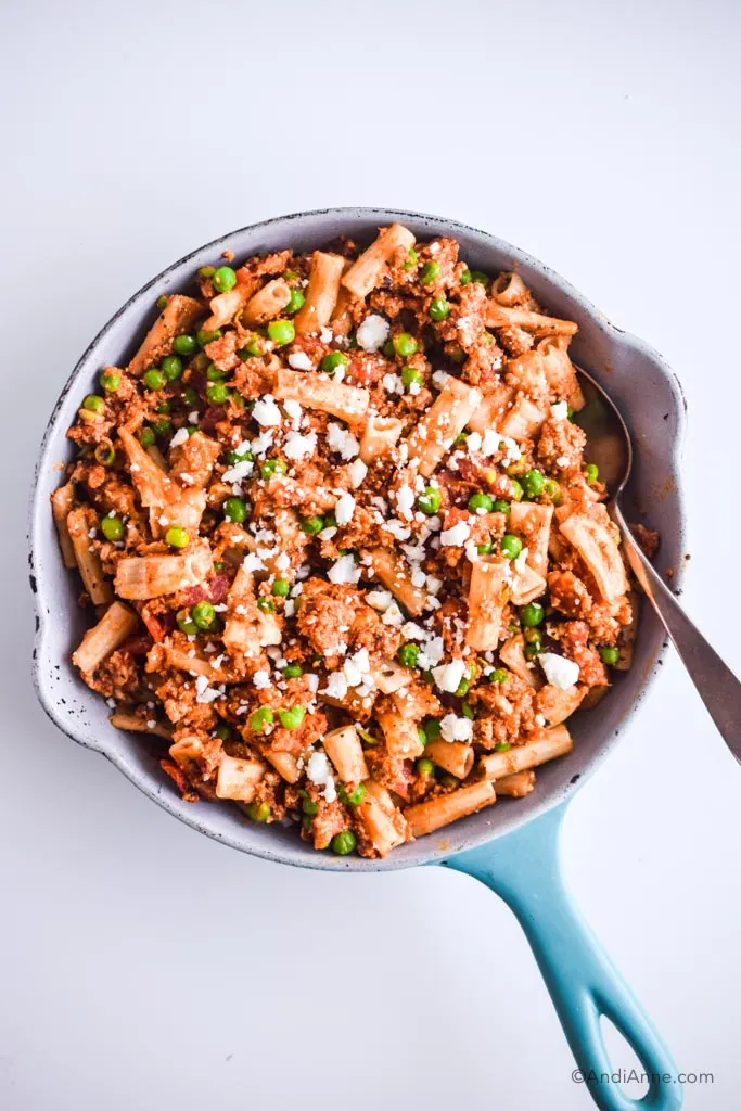 rigatoni, ground chicken peas and feta cheese in a blue and white skillet with silver spoon
