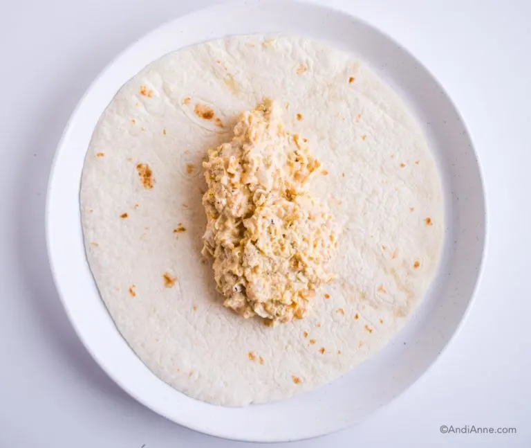 1 cup of mashed chickpea mixture in the center of flour tortilla on a white plate