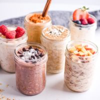 six mason jars with different flavors of overnight oat recipes and fruit toppings.