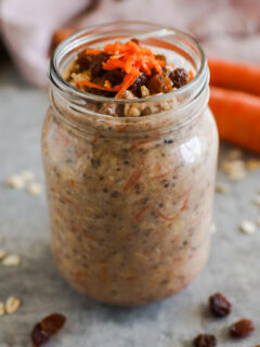 A mason jar with shredded carrots and raisins on top of overnight oats.