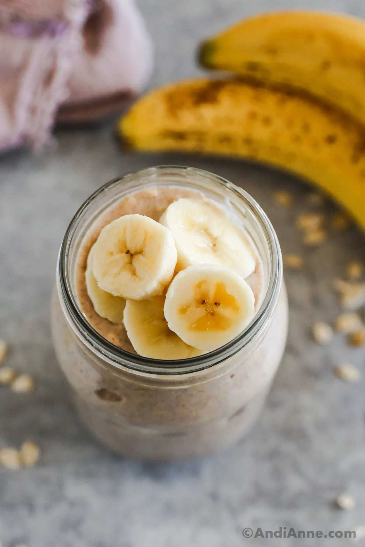 Looking into a mason jar with overnight oats and banana slices.