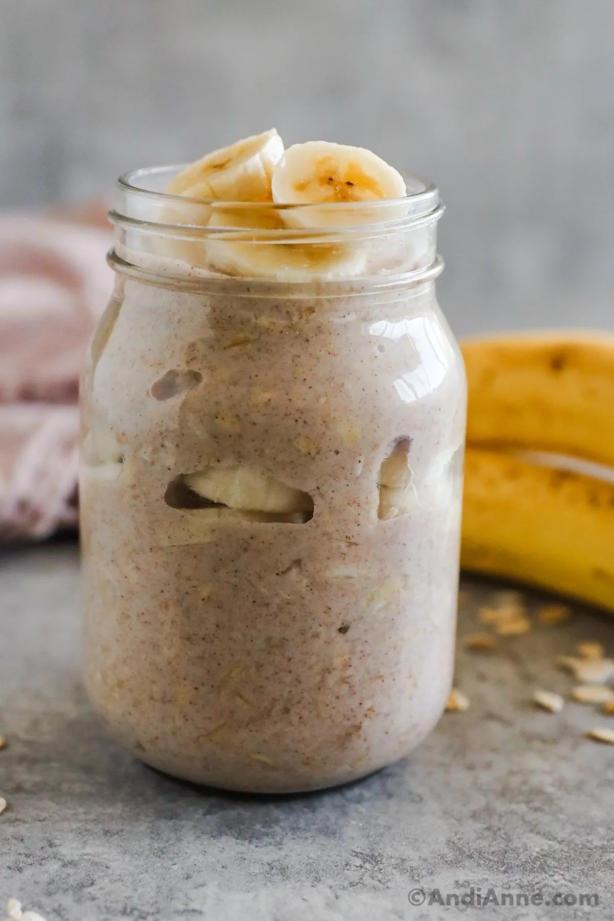 Banana overnight oats topped with banana slices, in a mason jar.