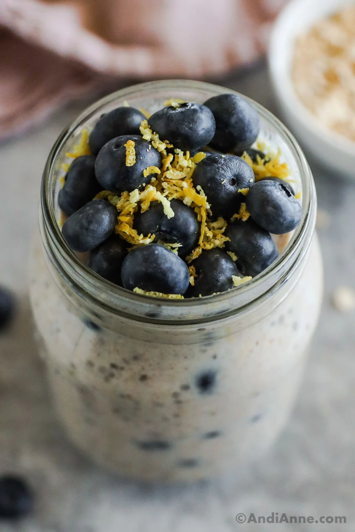 Looking into a mason jar with blueberries and lemon zest and overnight oats underneath.