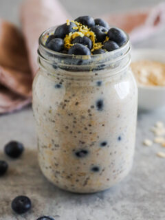 Mason jar with blueberry overnight oats inside, topped with fresh blueberries and lemon zest.