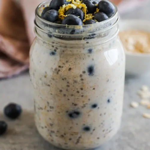 Mason jar with blueberry overnight oats inside, topped with fresh blueberries and lemon zest.