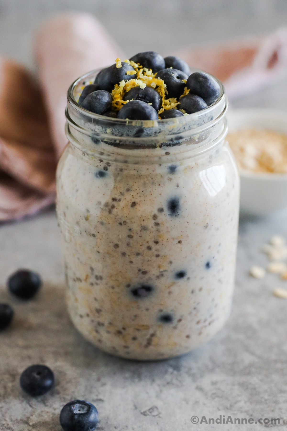 Blueberry overnight oats in a mason jar, topped with fresh blueberries and lemon zest.