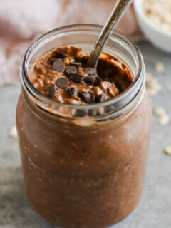 Mason jar with chocolate overnight oats topped with chocolate chips.