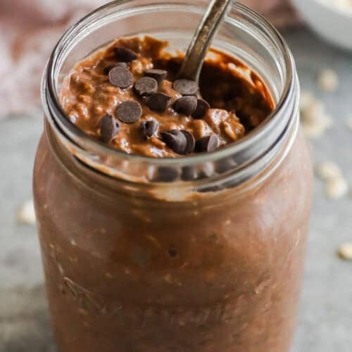 Mason jar with chocolate overnight oats topped with chocolate chips.