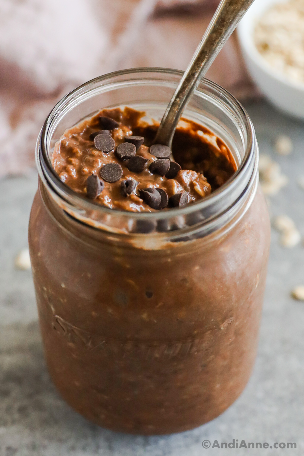 closeup view of a glass jar containing chocolate overnight oats with chocolate chips sprinkled on top. 
