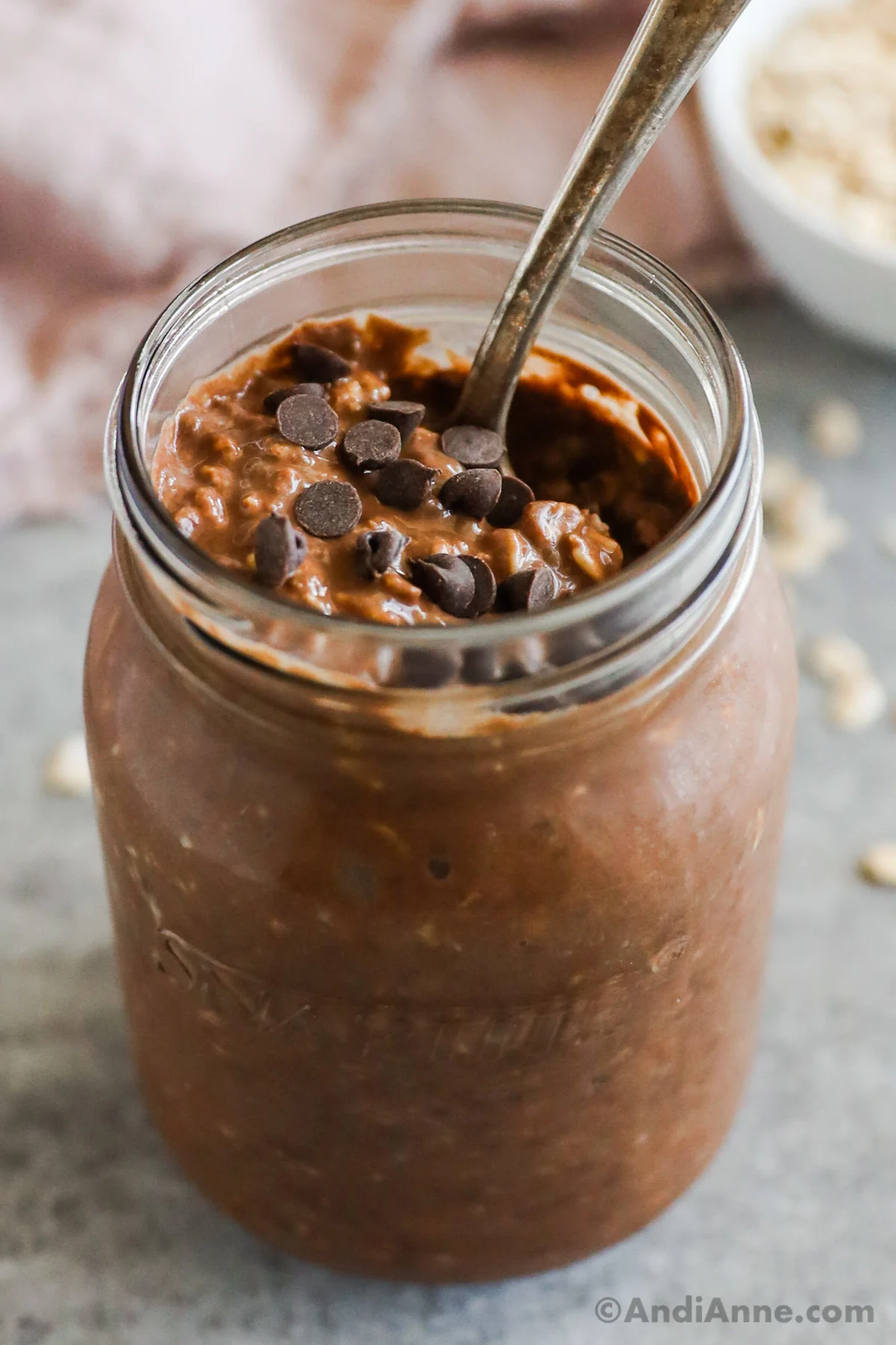 A mason jar with chocolate overnight oats and as spoon. 