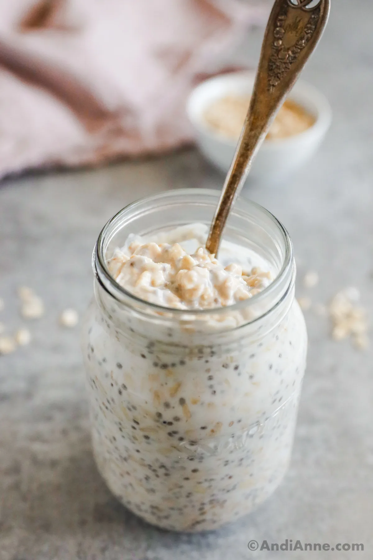A mason jar with overnight oats and a spoon.