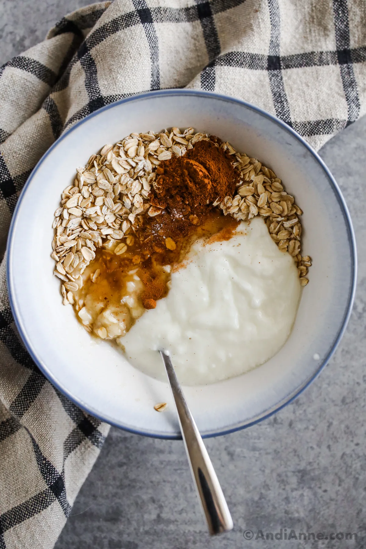 A bowl with rolled oats, yogurt, cinnamon, mashed banana and honey.