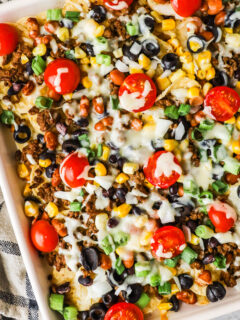 Ground beef sheet pan nachos with tomatoes, green onion and melted cheese