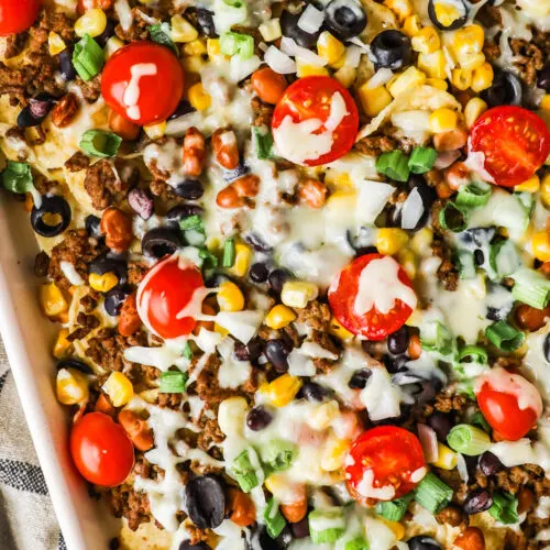 Ground beef sheet pan nachos with tomatoes, green onion and melted cheese