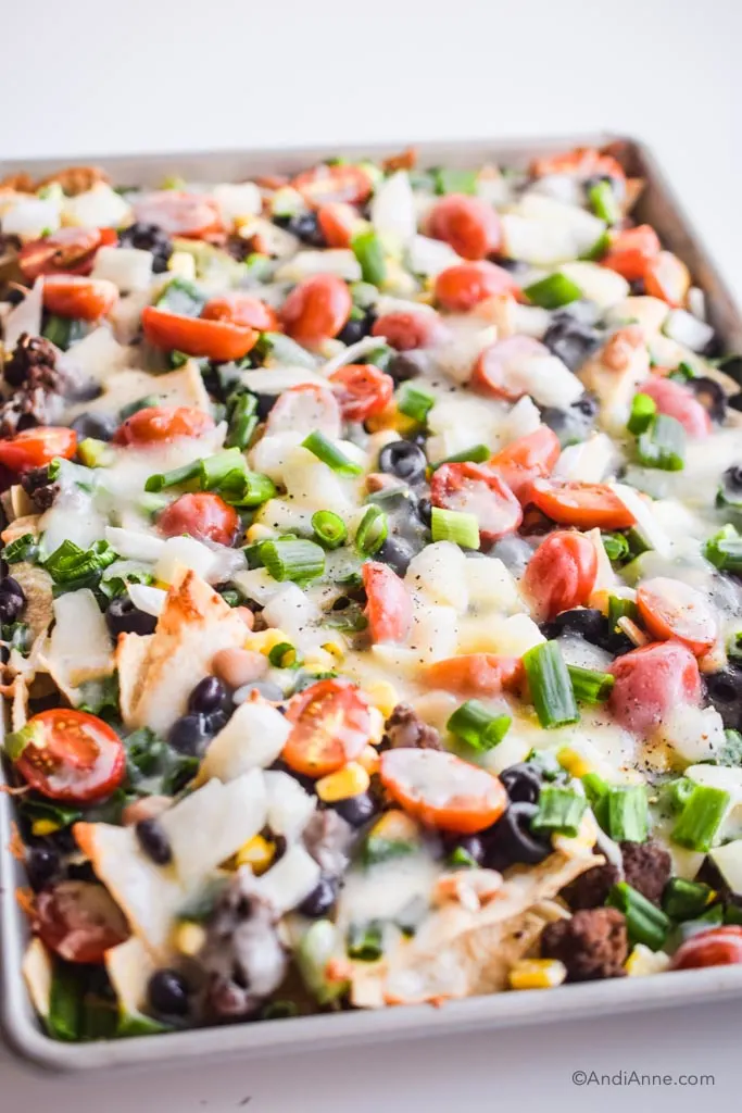 detail of melted cheese and all the veggies in the sheet pan nachos