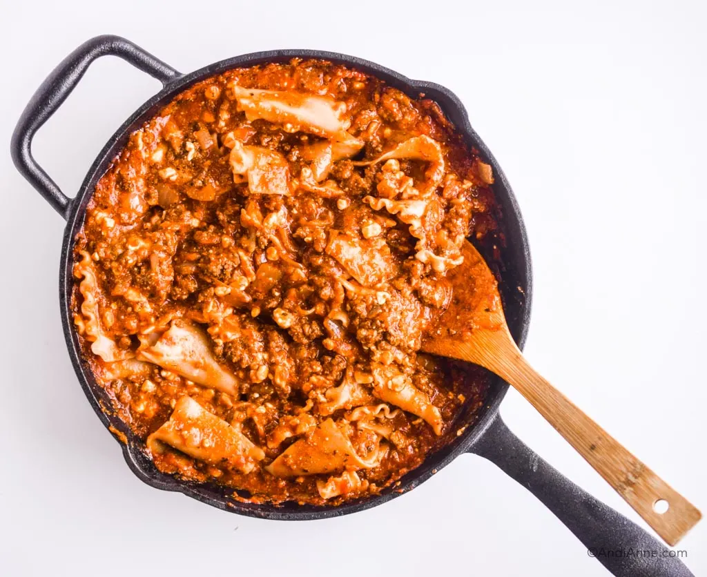 ground beef mixture with noodles stirred in skillet with wooden spoon