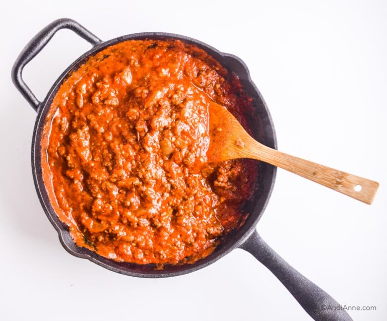 ground beef in pasta sauce in skillet with wooden spoon