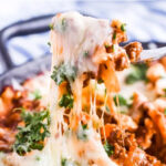 A fork pulling melted cheese from skillet lasagna recipe