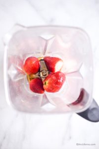 strawberries and maple syrup inside a blender cup