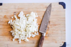 chopped onion on a cutting board with a knife