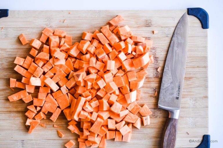 chopped sweet potato on a cutting board with a knife