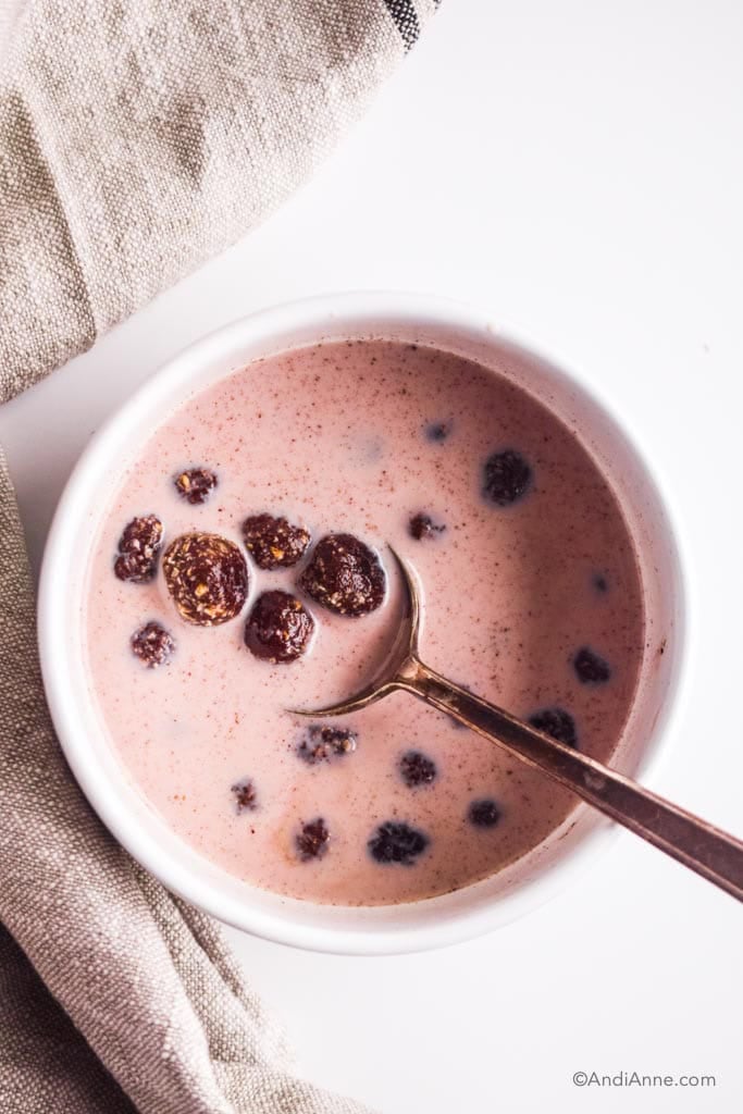 white bowl with homemade chocolate cereal and spoon. Milk is turning brown with from the chocolate.