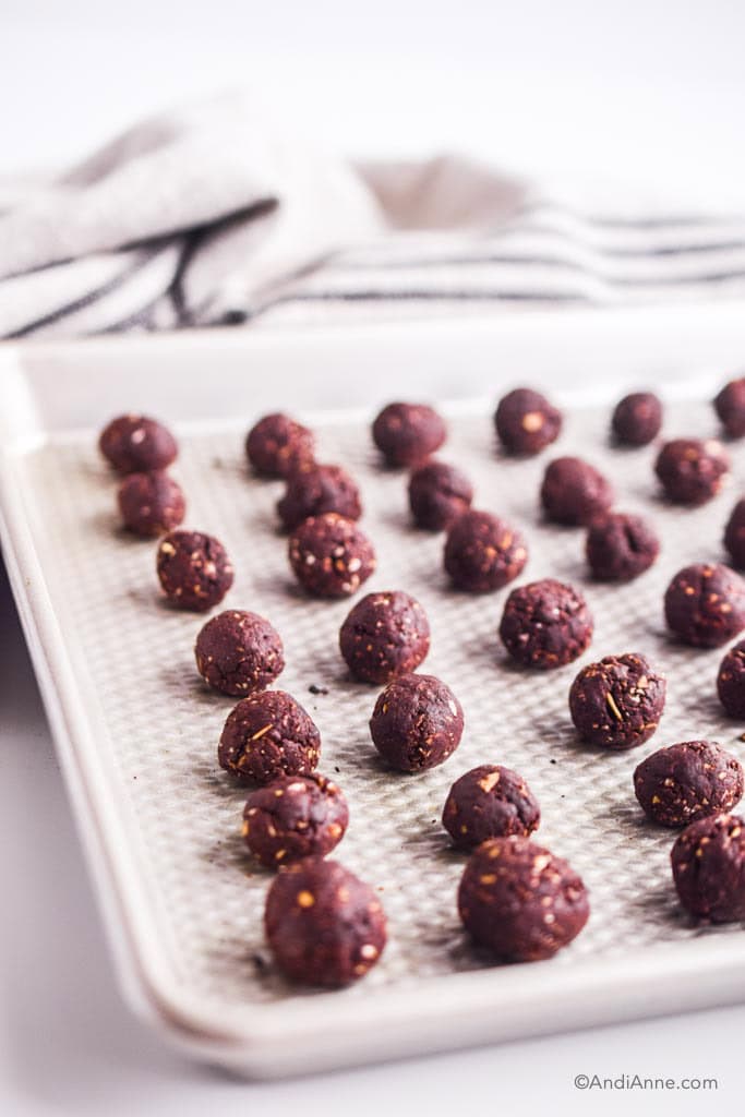 rolled chocolate balls lined up on a baking sheet.