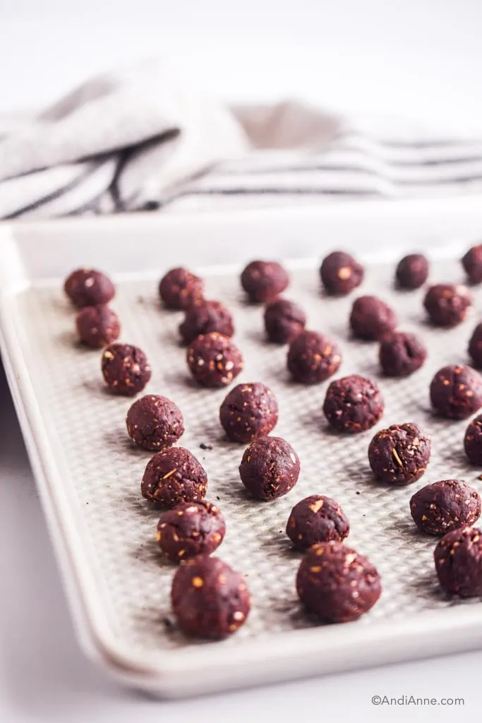 rolled chocolate balls lined up on a baking sheet.