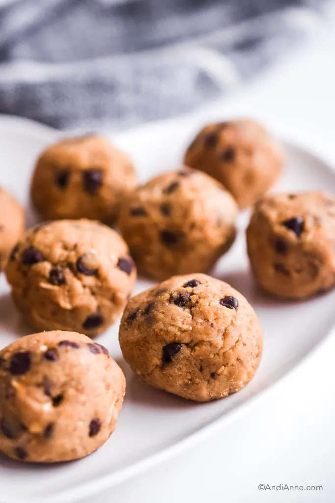 close up detail of cookie dough energy bites on a white plate with dark grey napkin in the background.