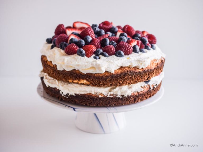 gluten free cake with whipping cream and fresh berries piled on top