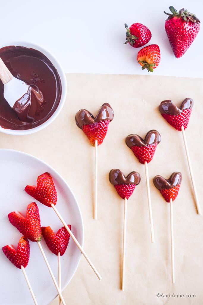 dipping strawberries in bowl of melted chocolate with spatula. Some are dipped and some undipped