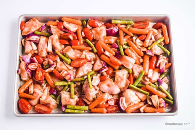raw chicken and chopped vegetables on a sheet pan