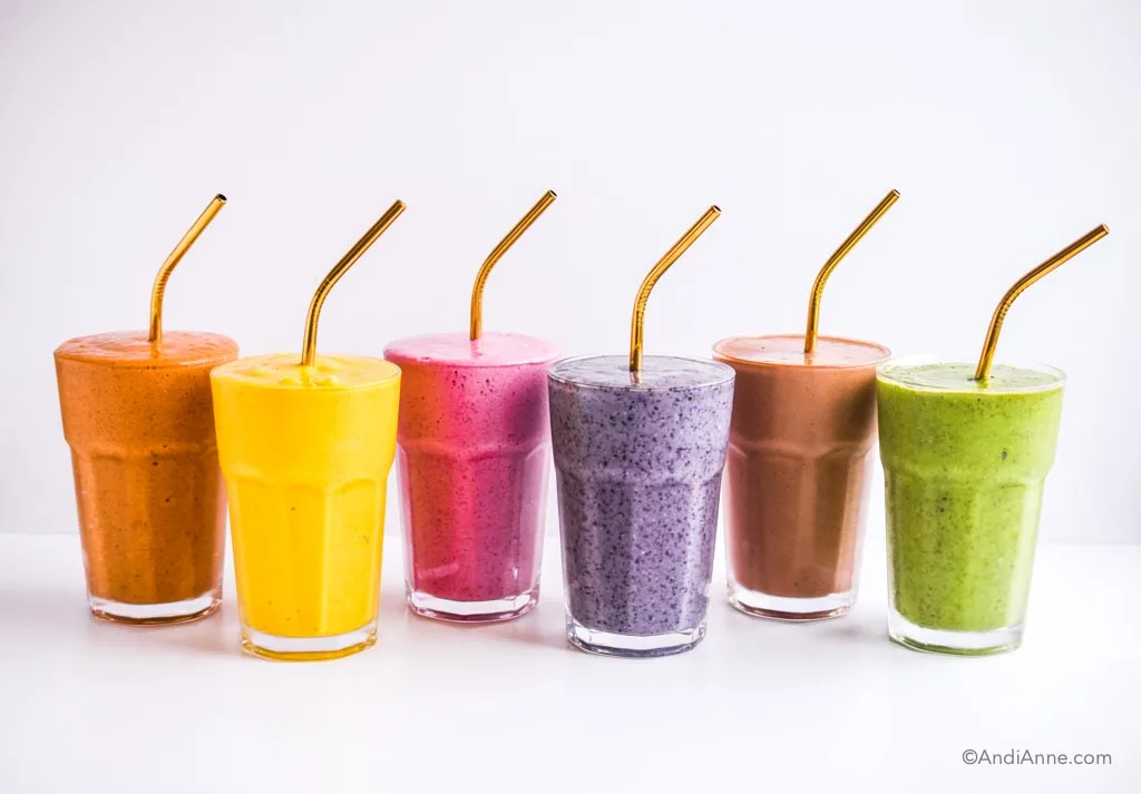 six colorful healthy smoothies in glasses with brass colored straws