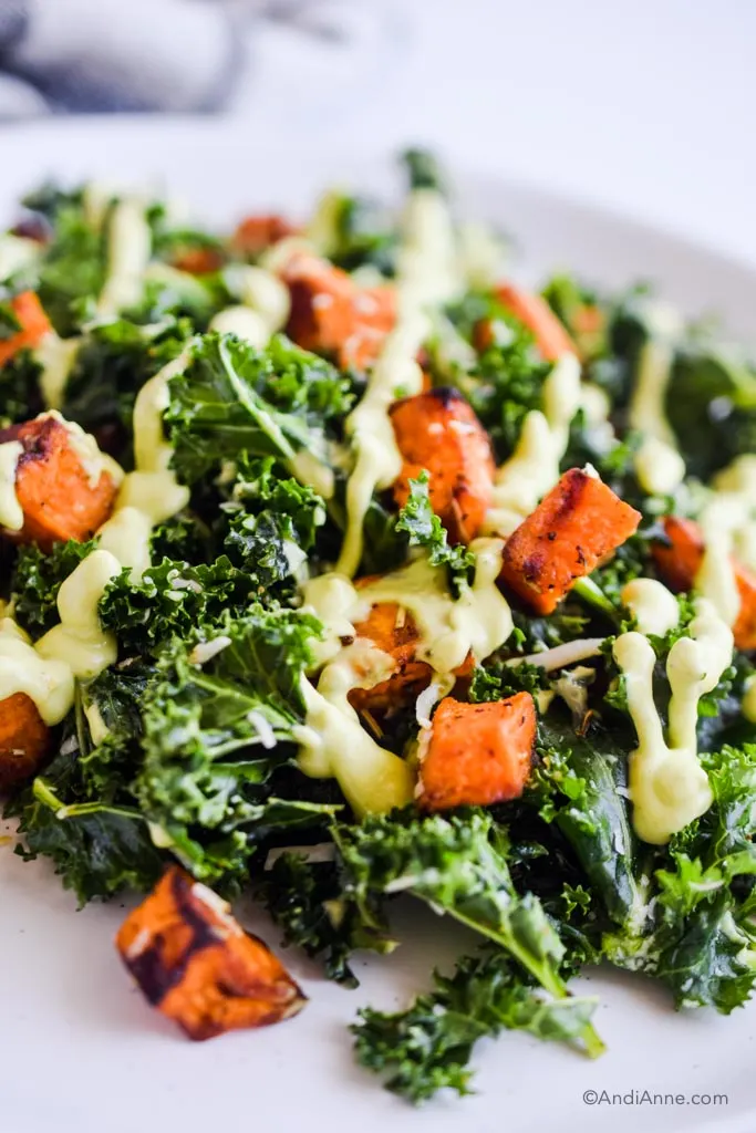 close up of kale and roasted sweet potato drizzled with avocado dressing