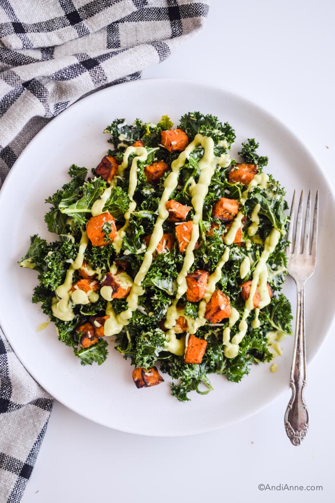 sweet potato kale salad with avocado dressing on a white bowl with a fork