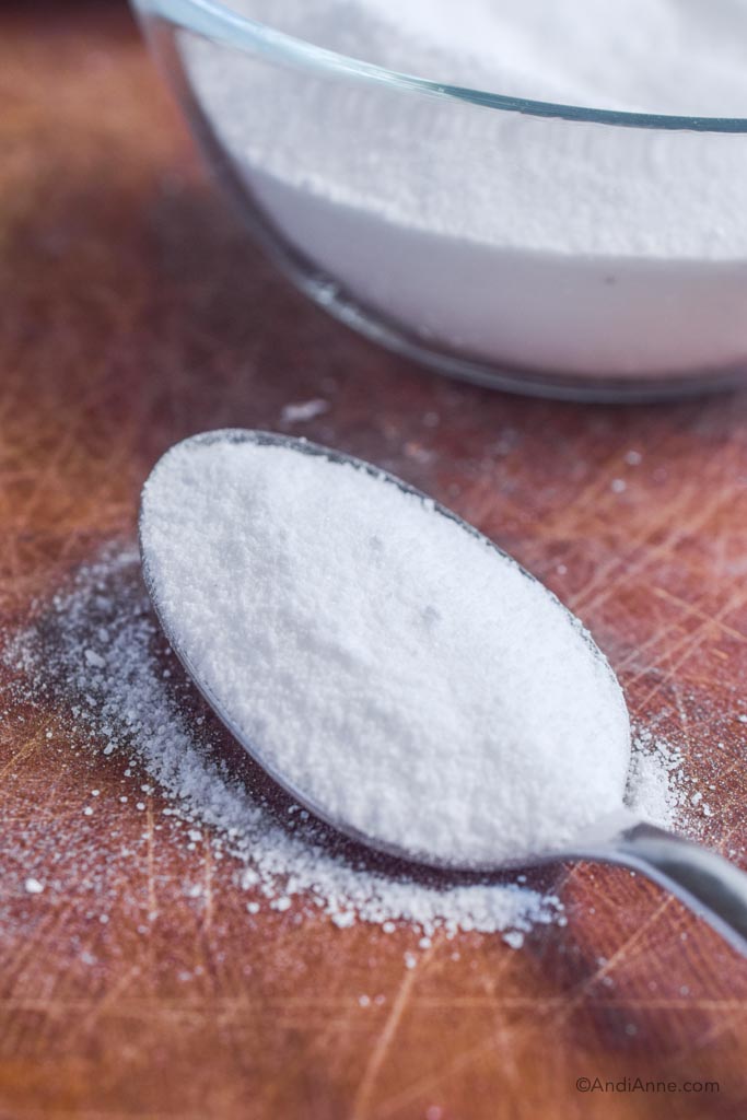 powdered sugar on a spoon on wood cutting board