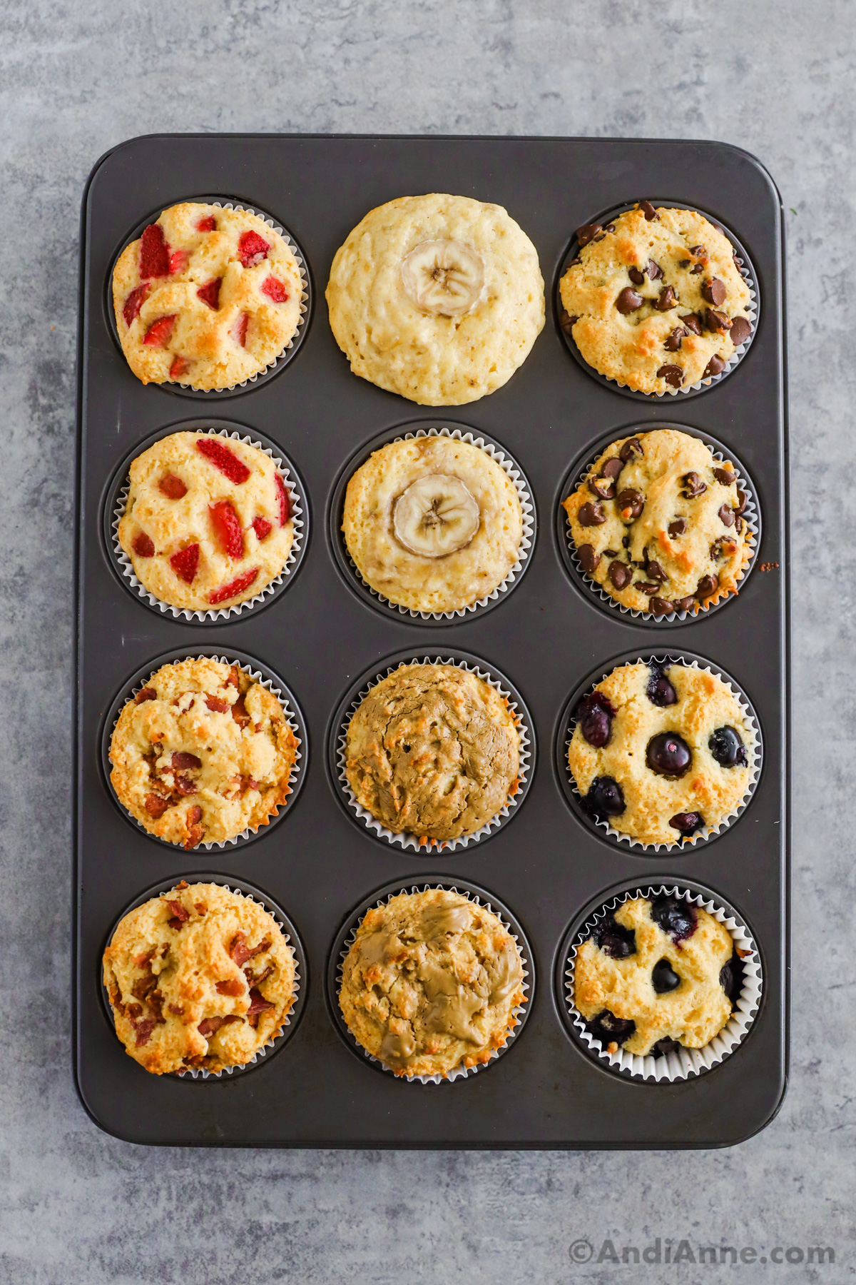 Baked pancake muffins with six flavors in a muffin pan including strawberry, banana, chocolate chip, bacon, nut butter and blueberry.