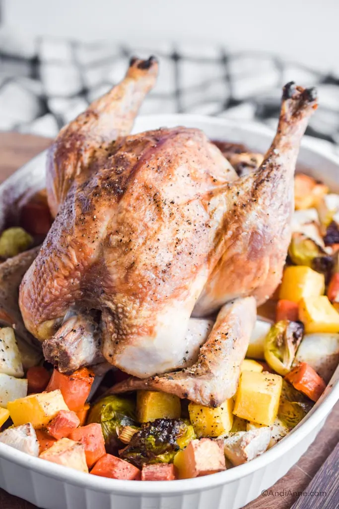 roasted chicken with root vegetables on a cutting board with kitchen towel in the background