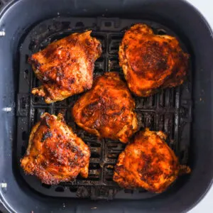 Cooked chicken thighs in an air fryer.