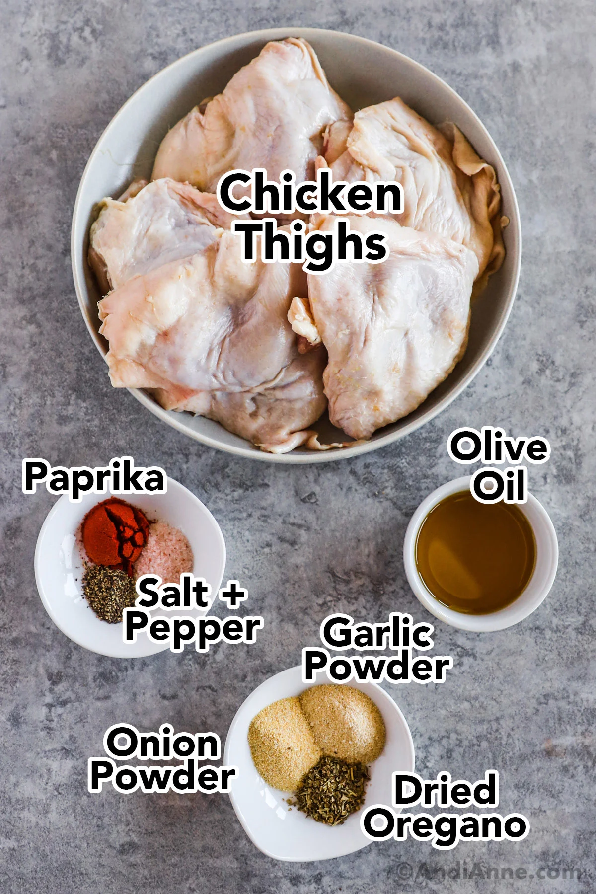 Recipe ingredients including raw chicken thighs on a plate, a cup of olive oil and small cups with spices.