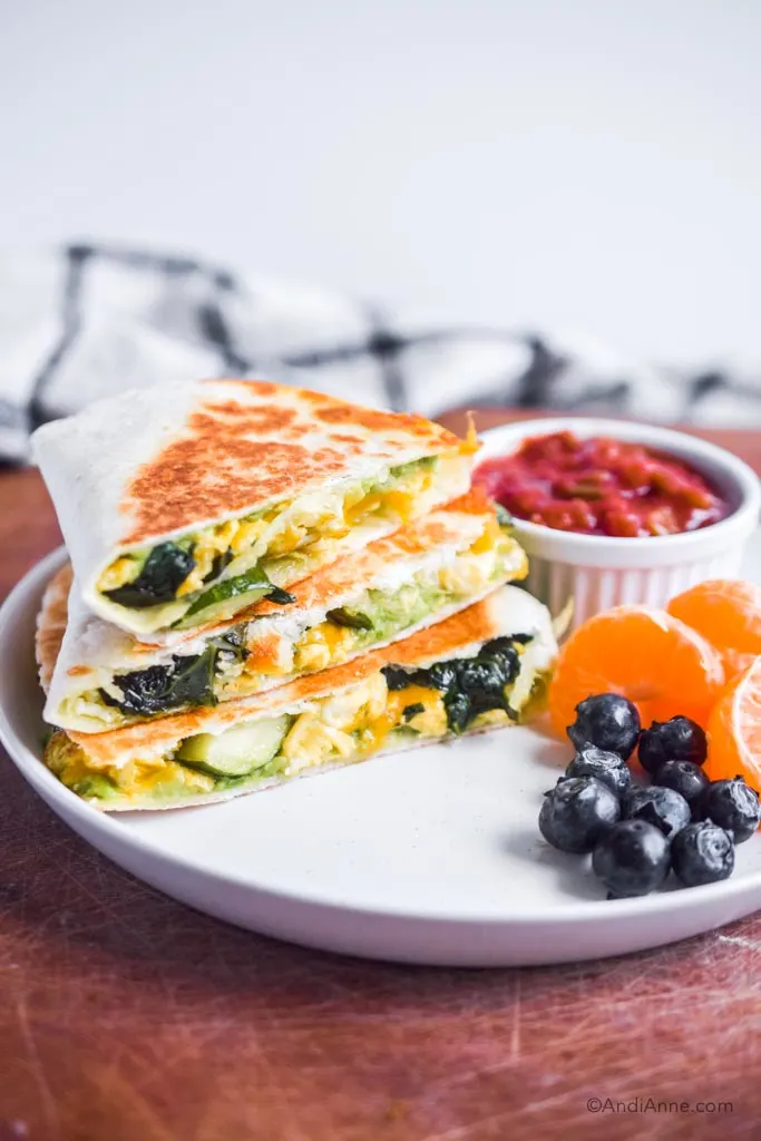 zucchini spinach breakfast quesadilla on a white plate with salsa, oranges and blueberries