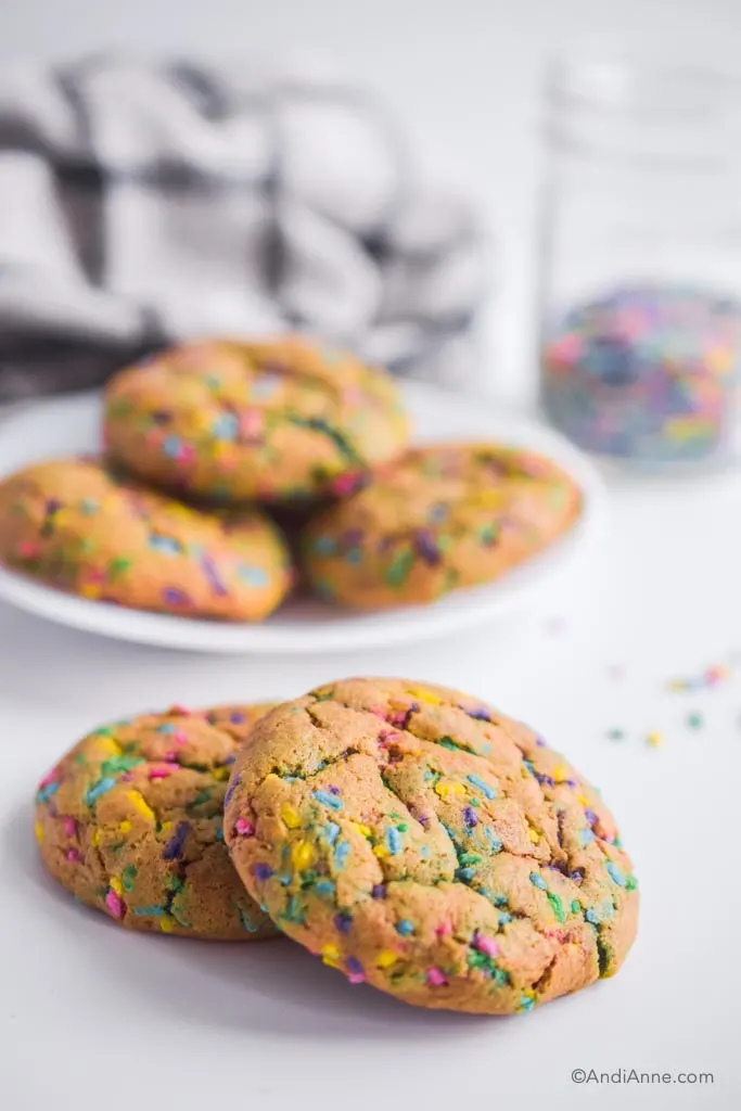 chickpea flour sprinkle cookies on a white counter with jar of sprinkles in the background
