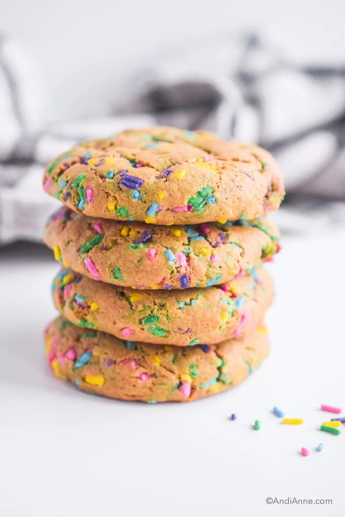 stacked chickpea sprinkle cookies with kitchen towel behind them