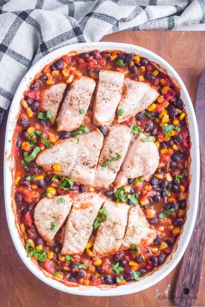 dump and bake salsa chicken recipe inside an oval baking dish. On top of a cutting board with kitchen towel.