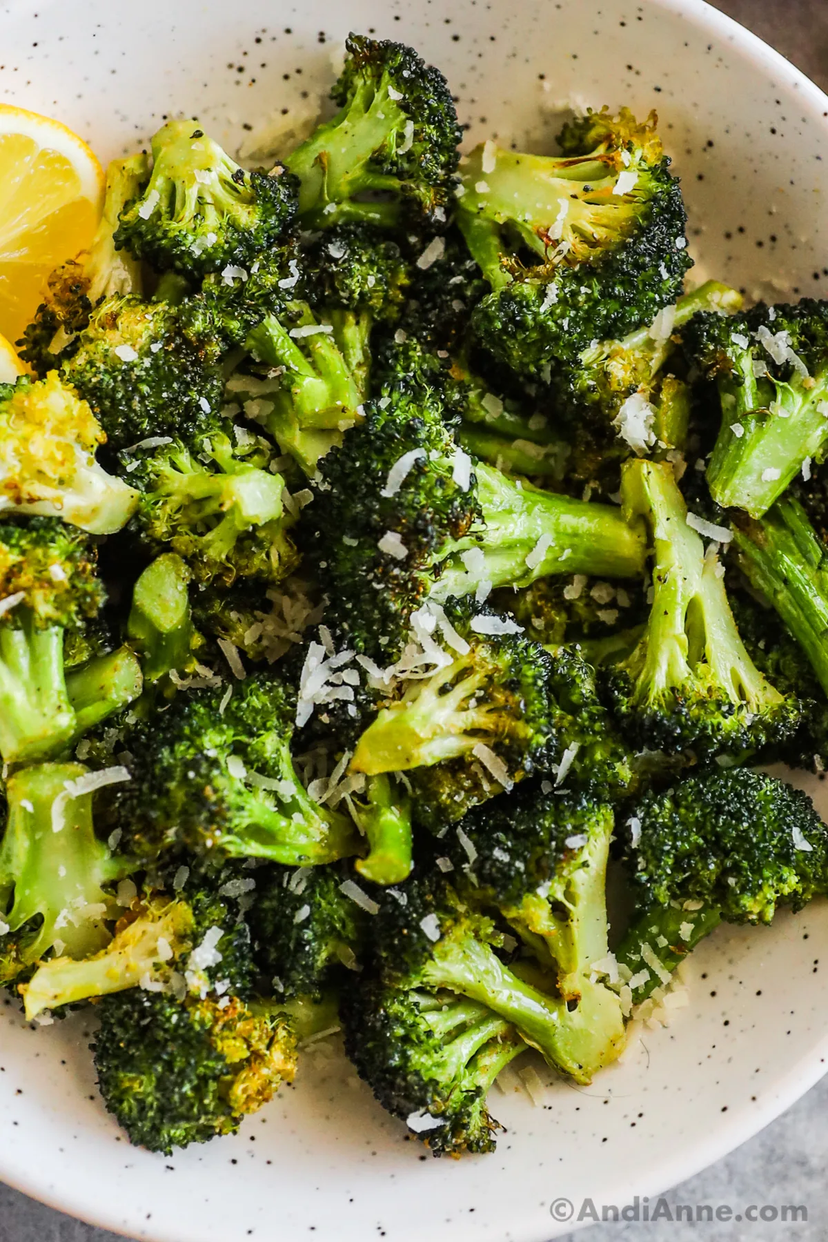 A bowl of air fryer broccoli with slices of lemon.