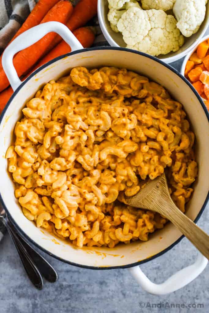 A pot of veggie mac and cheese with cauliflower, carrots and chopped butternut squash surrounding it.