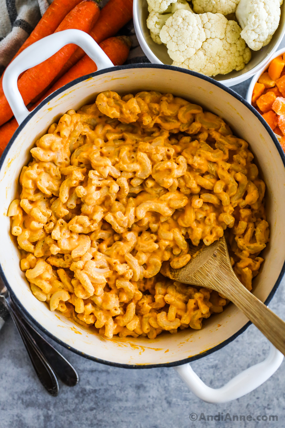 A pot of veggie mac and cheese with cauliflower, carrots and chopped butternut squash surrounding it.